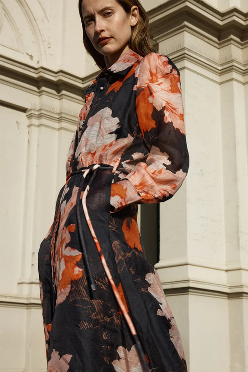 Model wears silk maxi shirt style dress with black and orange floral pattern  with tie waist 