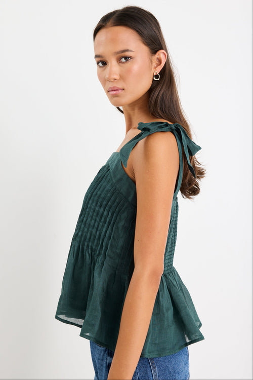 Woman wearing a green cami top and blue jeans