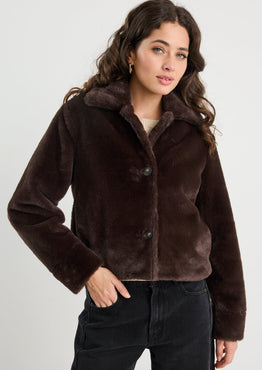 Woman wearing a brown faux fur jacket against a white background