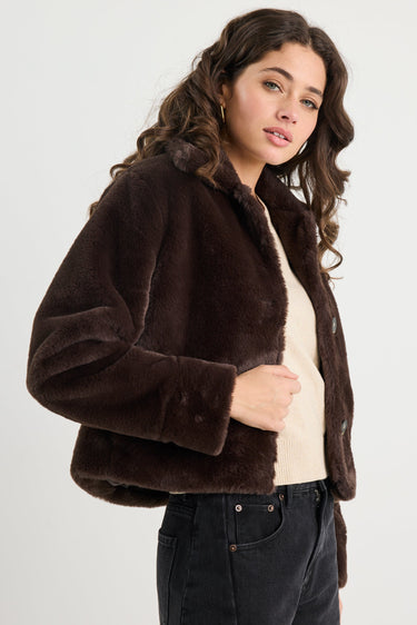 Woman wearing a brown faux fur jacket on a white background