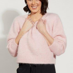 Woman wearing pink fluffy long sleeve jumper and black pants