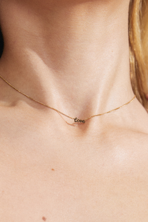 model wearing a gold chain adjustable necklace with a pendant reading 