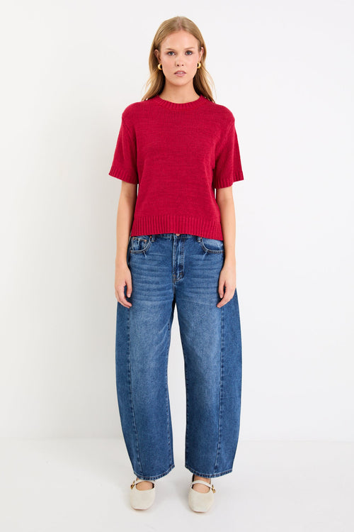 Model wearing a cherry red short sleeve knit tee with a crew neckline and side splits.