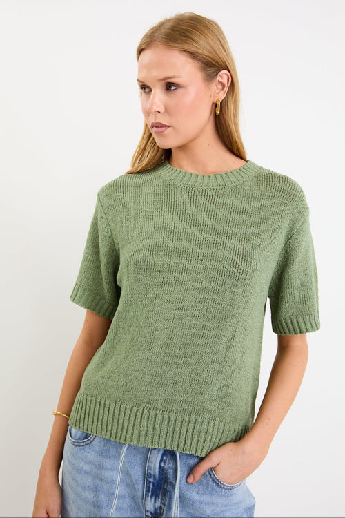 Woman wearing a green knitted sweater against a white background