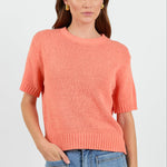 Woman wearing a orange tee and blue jeans on a white background