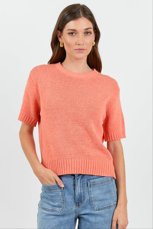 Woman wearing a orange tee and blue jeans on a white background