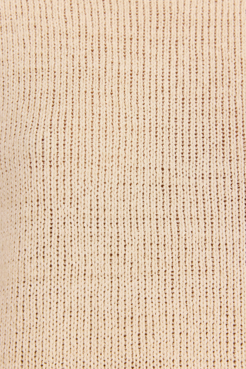 Close-up of a ribbed knit fabric in a warm cream or light beige color, showing the detailed vertical texture.