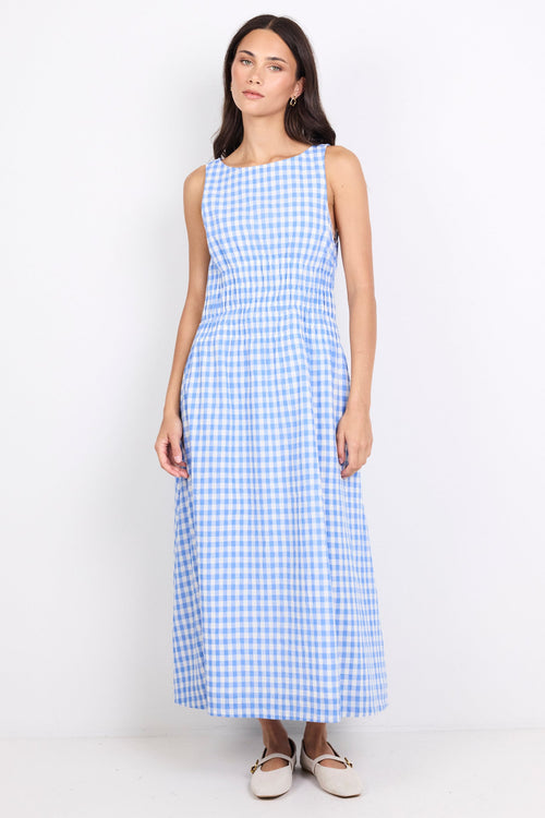 A woman modeling a sleeveless, knee-length blue and white gingham dress against a plain white studio background.
