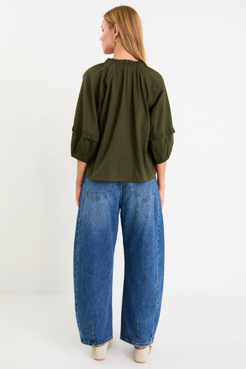 Person wearing a green shirt and blue jeans on a white background