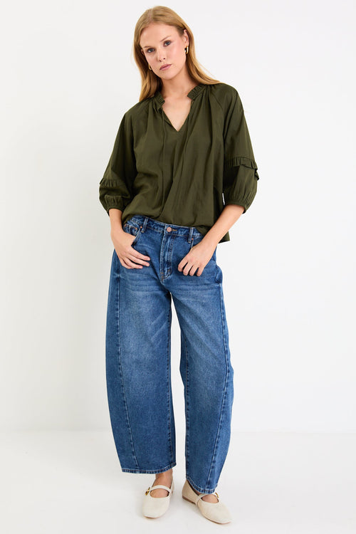Woman wearing a green shirt and blue jeans on a white background