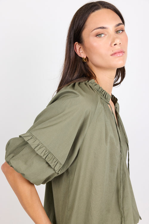 Woman wearing an olive green blouse against a white background