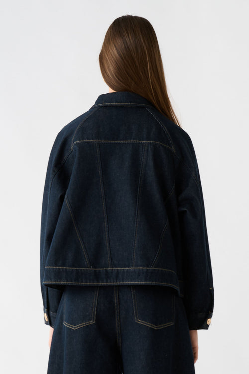 Person wearing a dark denim outfit on a white background