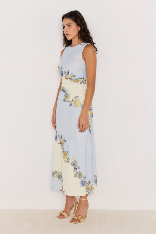 Woman wearing a sleeveless dress with floral pattern on a plain background