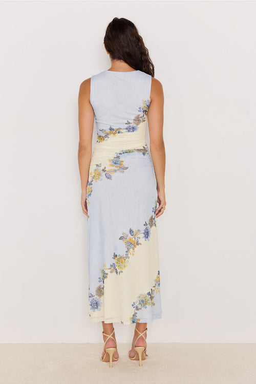 Woman wearing a sleeveless dress with floral pattern on a plain background