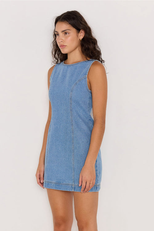 Woman wearing a blue denim dress against a white background