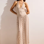 Woman wearing a patterned dress standing against a plain wall.