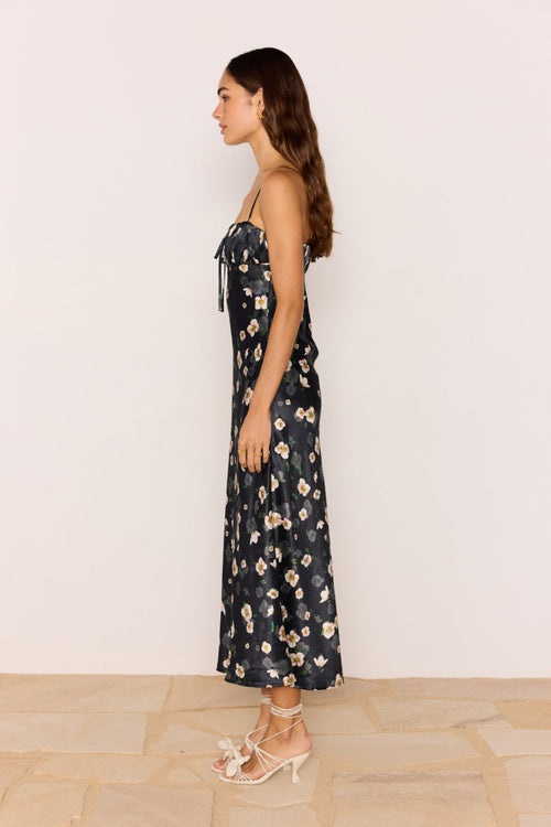 Woman wearing a floral dress standing against a plain background