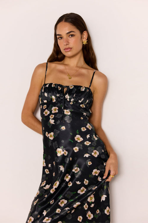Woman wearing a black floral dress against a plain background