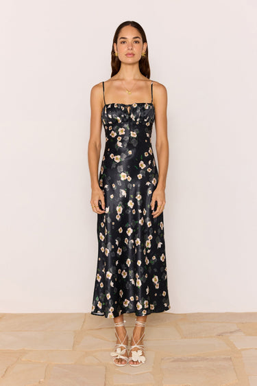 Woman wearing a black floral dress against a plain background