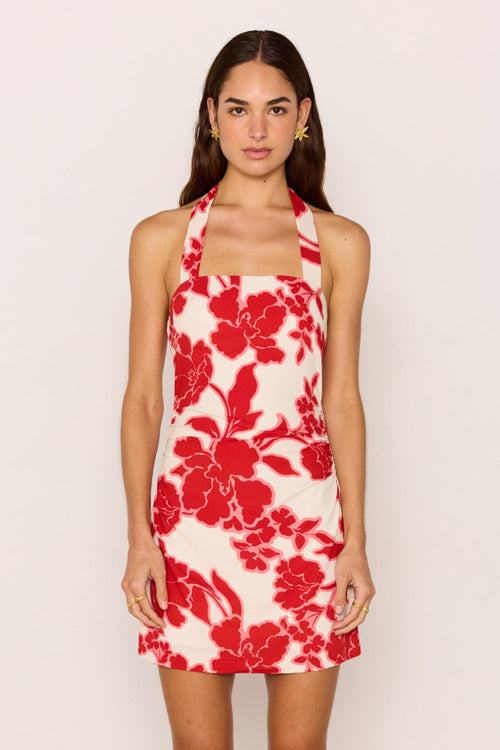 Woman wearing a red floral dress against a plain background