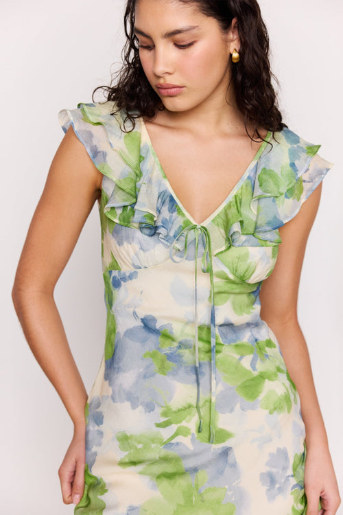 Woman wearing a floral dress with green and blue flowers on a white background