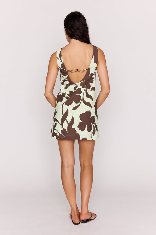 Woman wearing a floral dress with a cutout back on a plain background