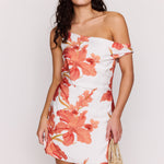 Woman wearing a floral off-shoulder dress against a plain background