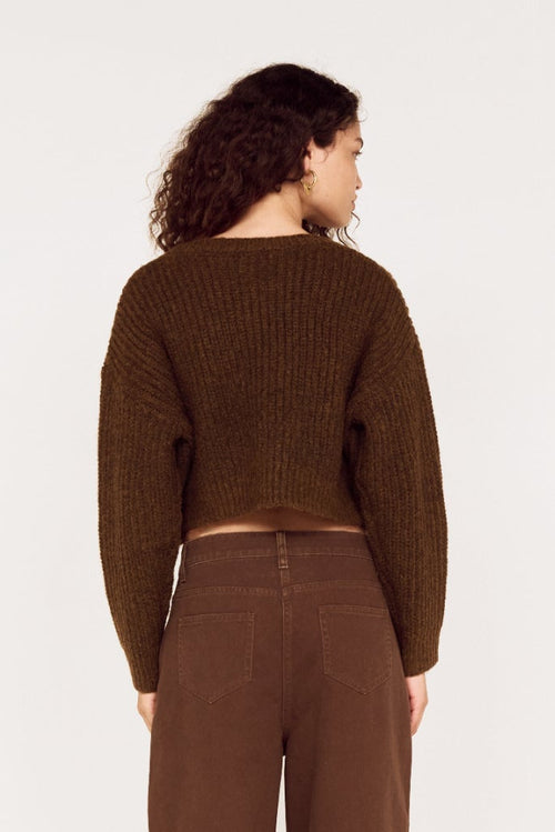 Person wearing a brown ribbed sweater and pants on a white background