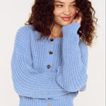 Woman wearing a light blue knitted sweater on a white background