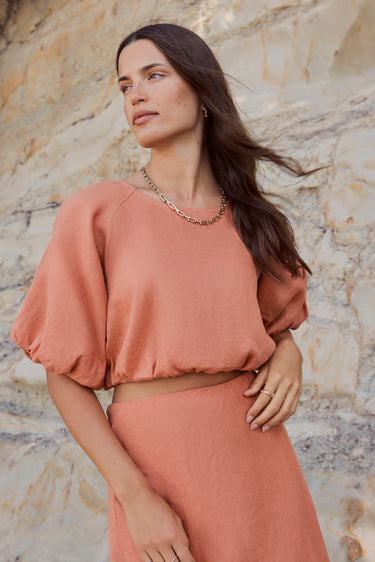 model wears an orange linen top