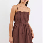 Woman wears a chocolate brown mini dress with pleated bodice
