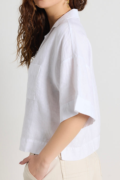 model wears linen white shirt and ecru shorts