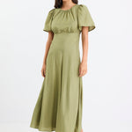 Woman wearing a long green dress with gathering and puff sleeves