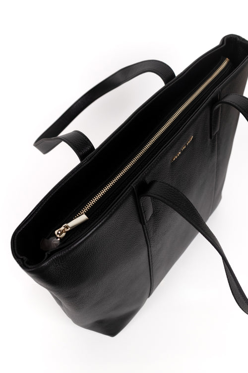 Black leather tote bag with a top zipper and shoulder straps, photographed from an overhead angle on a white background.