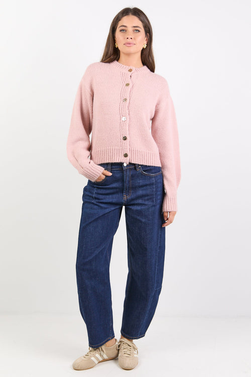 Women wearing pink cardigan and indigo jeans on white background.
