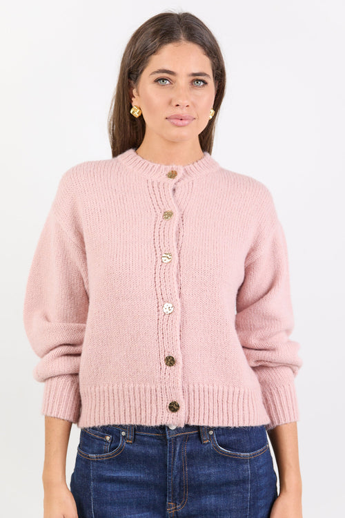 Woman wearing a pink cardigan with button details on a white background