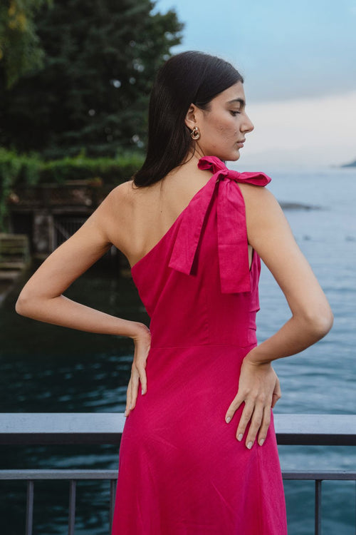 model wears a one shoulder pink midi dress