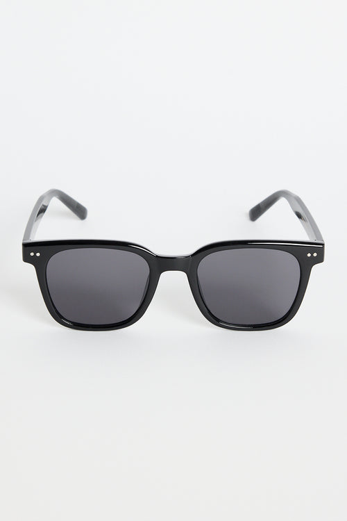 Glossy black classic square sunglasses with dark tinted lenses and subtle metal detailing, photographed on a white background.