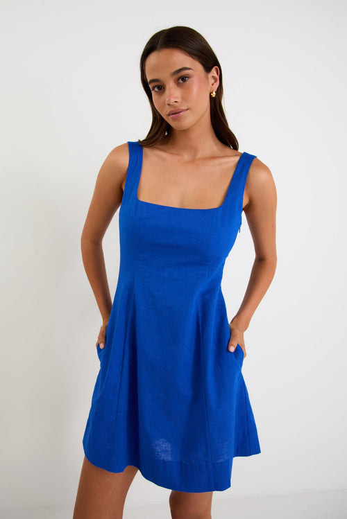 Model wearing an electric-blue sleeveless mini dress with a square neckline and a shirred back