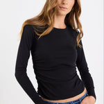 Woman wearing a black long-sleeve top and blue jeans on a white background