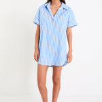 Model wearing a blue and white striped short sleeve mini shirt dress with a button front and collar.