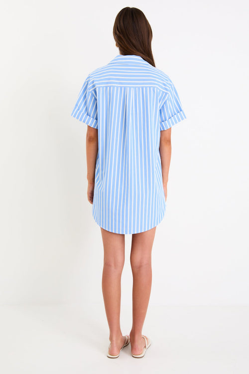 Model wearing a blue and white striped short sleeve mini shirt dress with a button front and collar.
