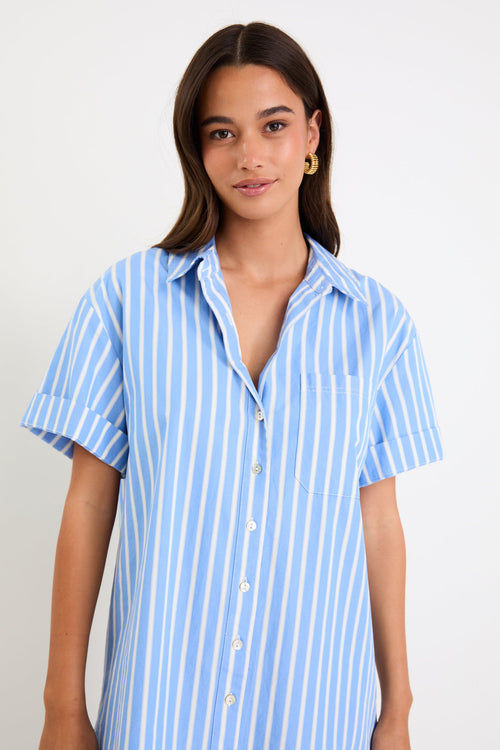 Model wearing a blue and white striped short sleeve mini shirt dress with a button front and collar.