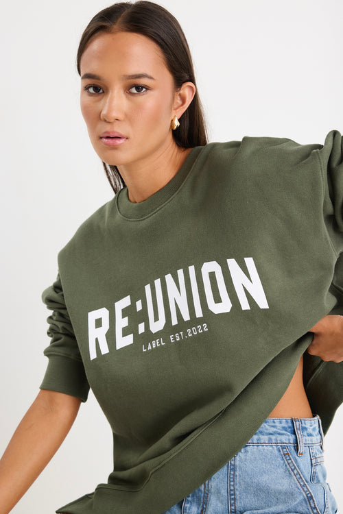 Woman wearing a khaki green oversized sweatshirt with 