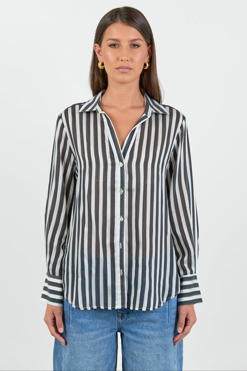 Woman wearing a black and white striped shirt with blue jeans on a white background