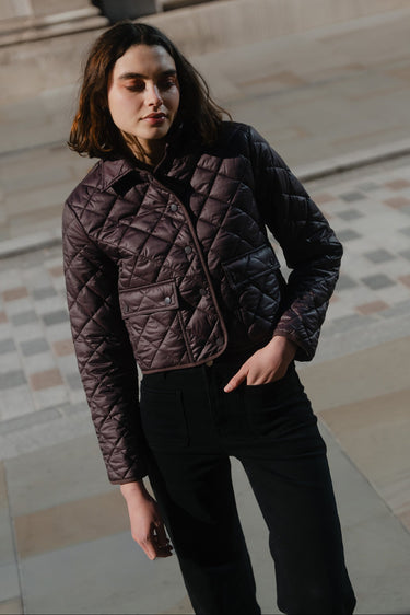 Woman wearing a quilted jacket standing on a stone pavement