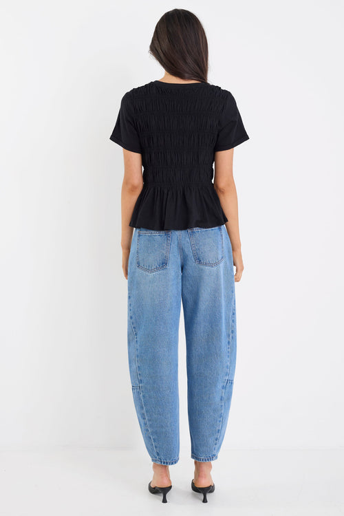 Person wearing a black top and blue jeans on a white background