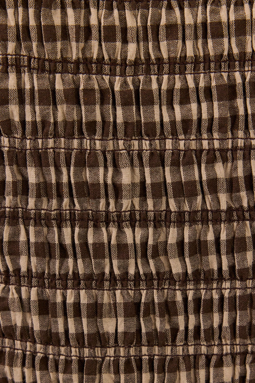 Close-up of a brown and beige gingham fabric with horizontal smocked or gathered stitching.