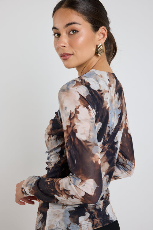 model wears a brown and blue mesh floral top with a black maxi skirt