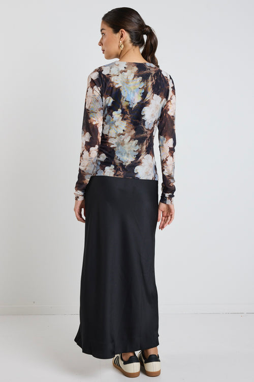 model wears a brown and blue mesh floral top with a black maxi skirt